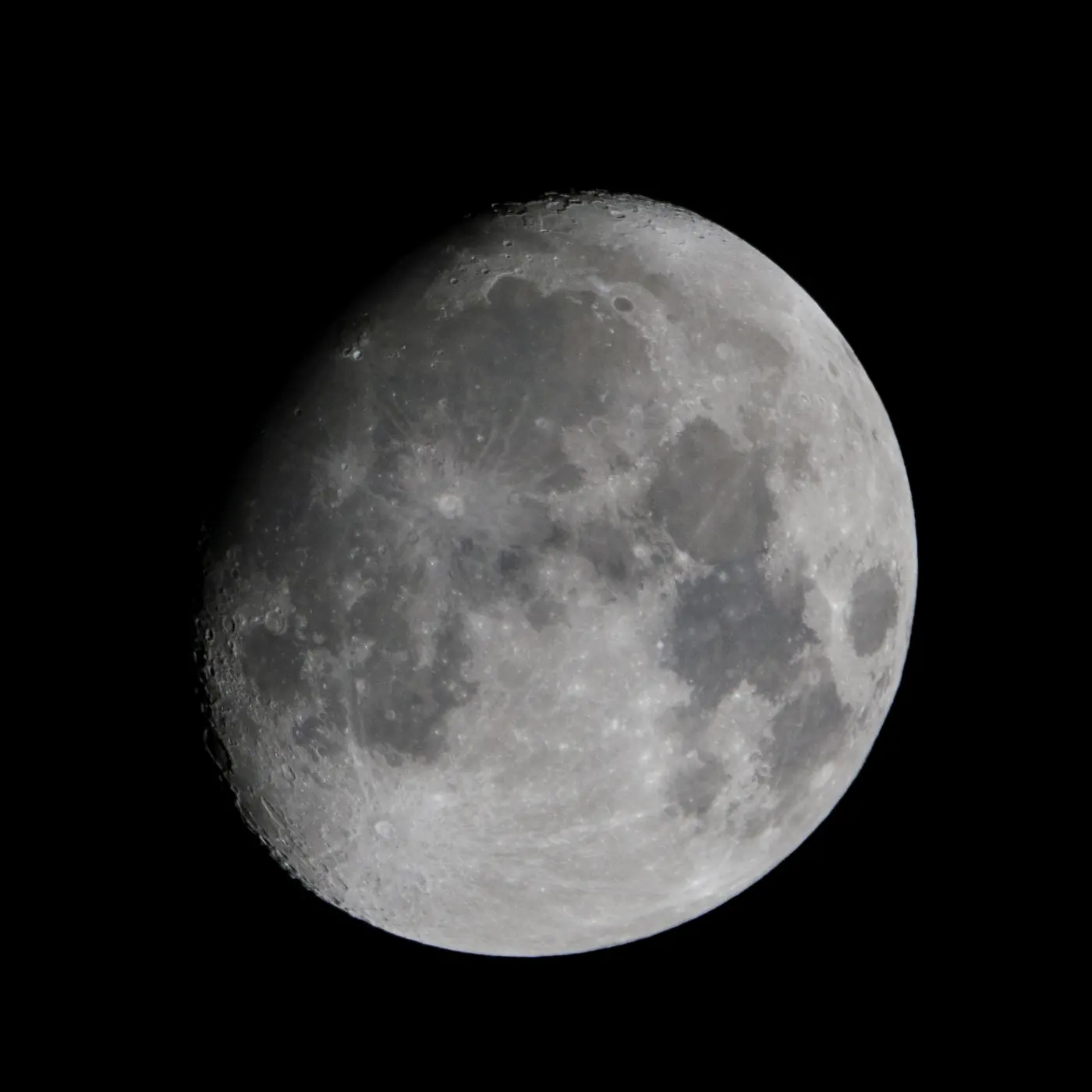 A close telescopic photograph of the waxing moon against a black sky.