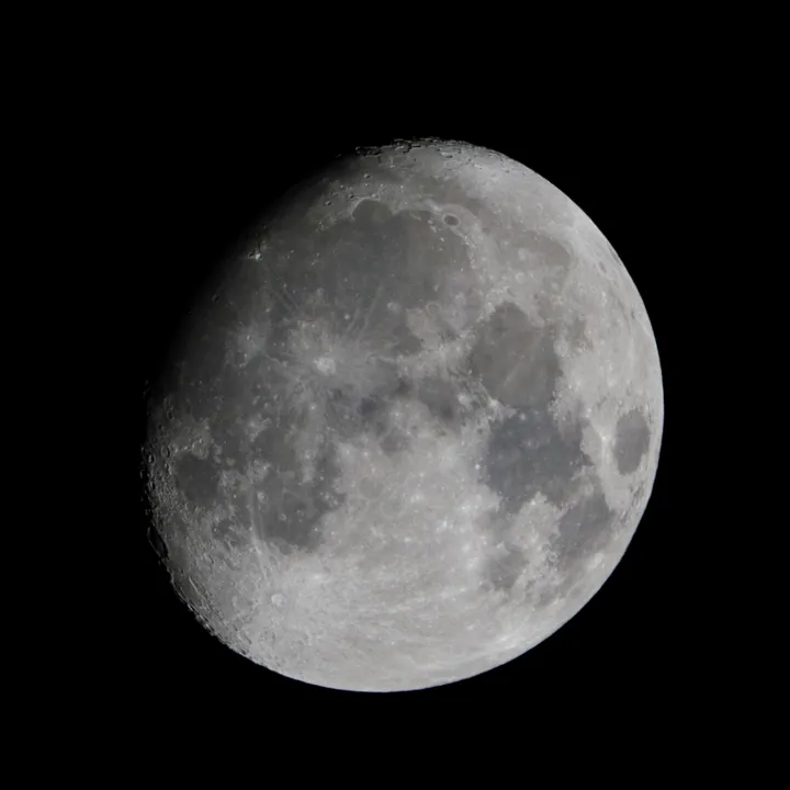 A close telescopic photograph of the waxing moon against a black sky.