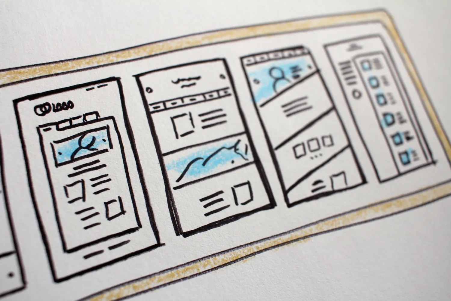 A close-up photograph of hand-drawn website wireframes on paper.
