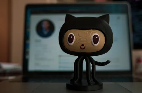 A handmade GitHub Octocat figure standing in front of a computer screen.